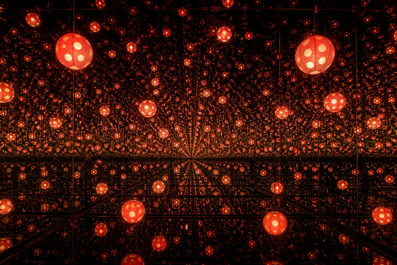 An infinity mirror room filled with warm red polka-dotted lanterns reflected endlessly toward a dark vanishing point